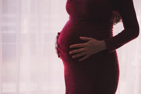 Silhouette of a pregnant woman gently holding her belly, emphasizing motherhood and anticipation.